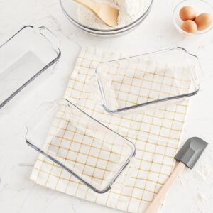 glass loaf pans and a spatula on a yellow checked towel