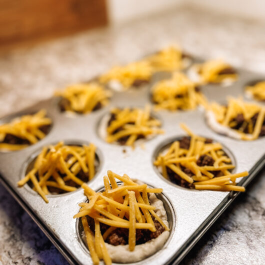 Unbaked cheeseburger bites in a muffin tin.