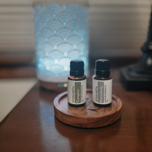 Two essentials oils in front of a diffuser.