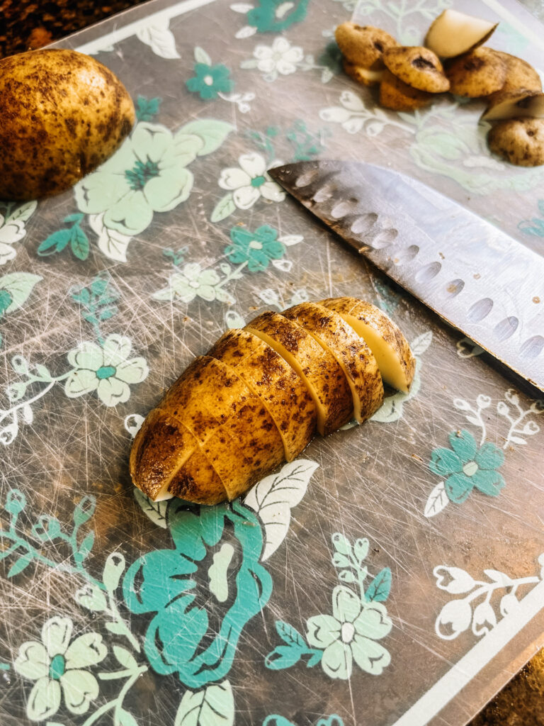 Yukon gold potato cut on a cutting mat with blue flowers