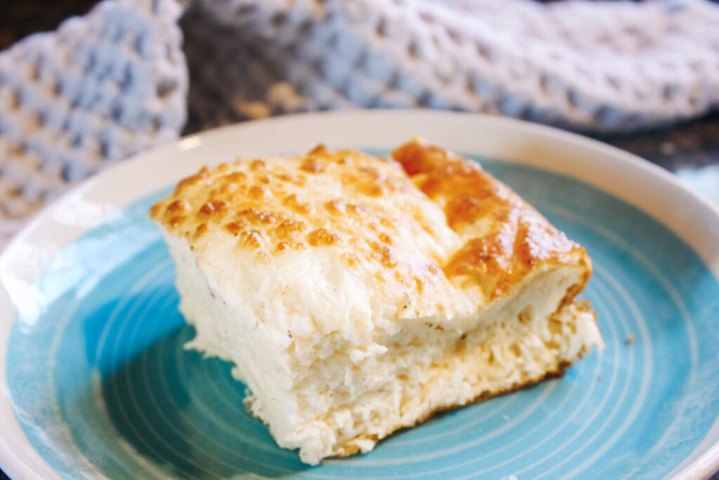 Slice of egg casserole on a blue plate.