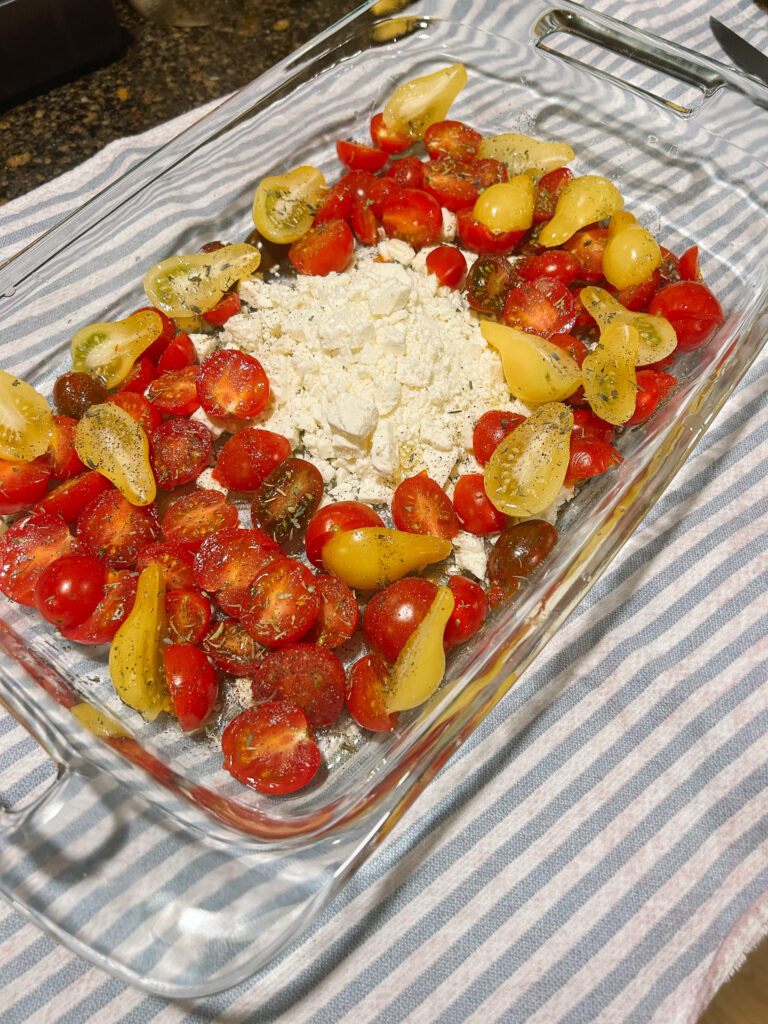 Sliced cherry tomatoes and feta cheese in a baking dish.